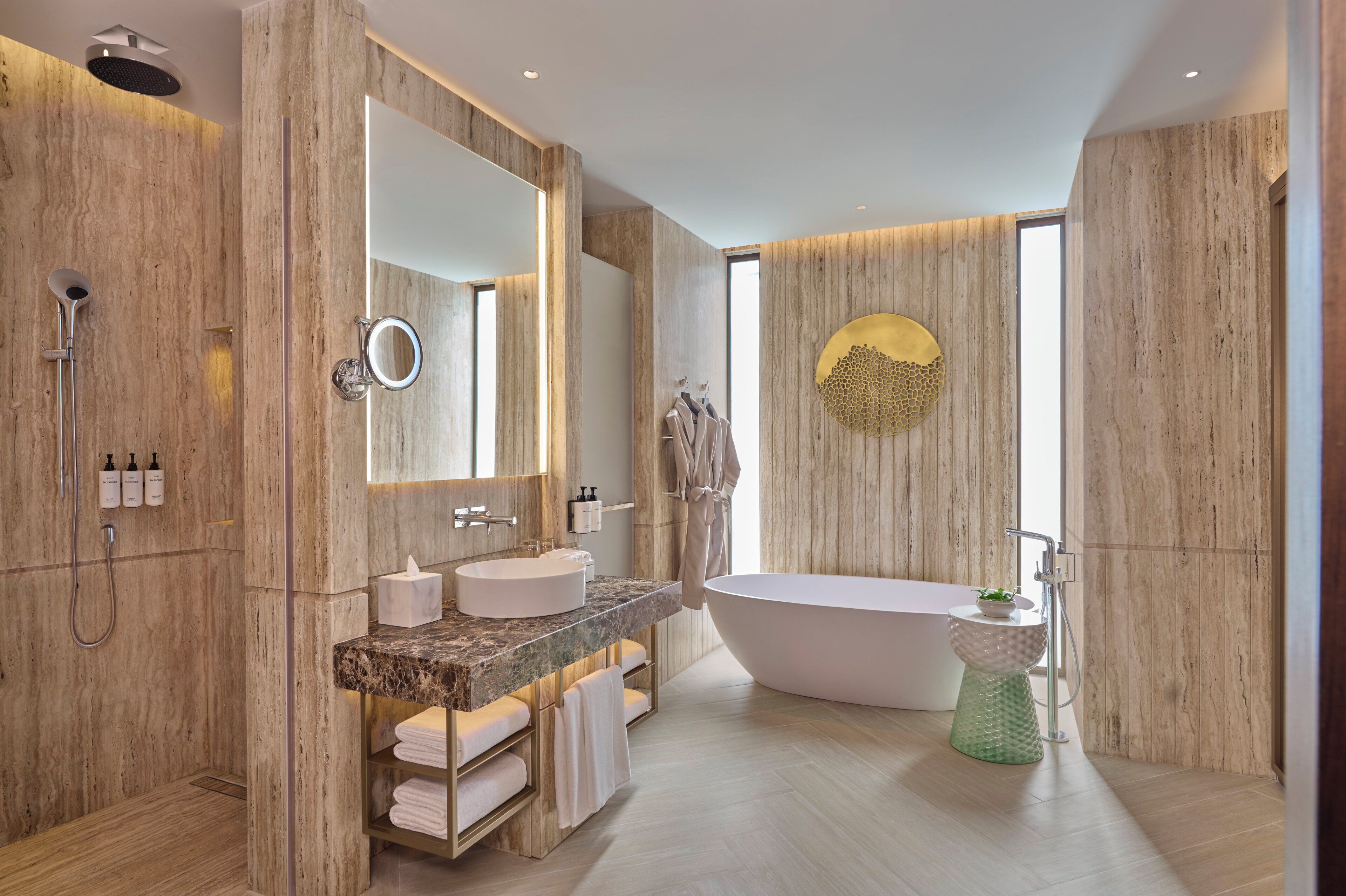 A modern bathroom with a freestanding bathtub, a large mirror, and a vanity with a marble countertop.