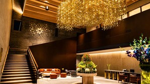 A modern lobby with a staircase, seating area, and a central decorative piece.