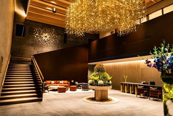 Eine moderne Lobby mit Treppe, Sitzgelegenheit und einem zentralen Dekorationsobjekt.