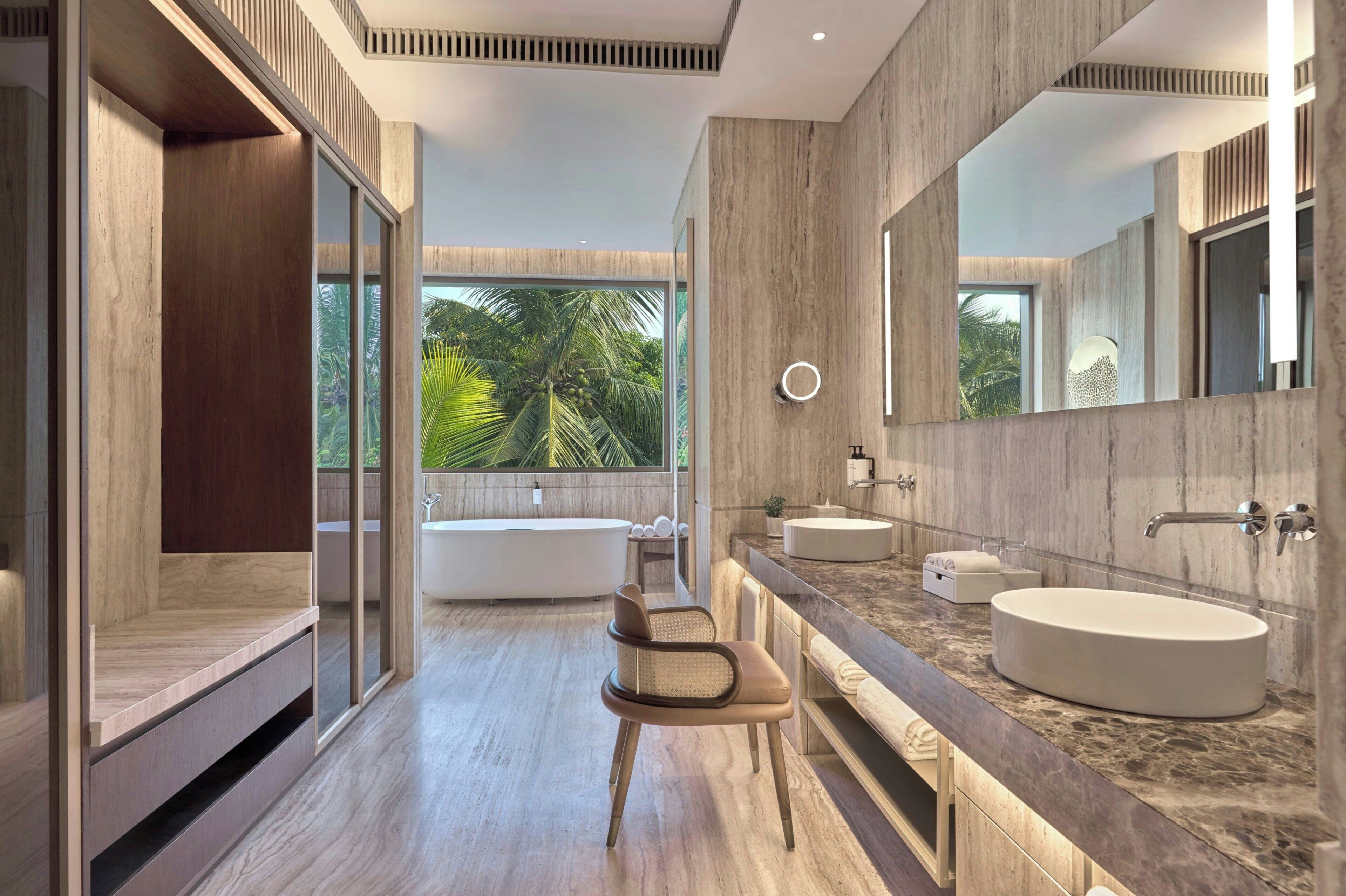 A modern bathroom with a large mirror, two sinks, a bathtub, and a shower area.