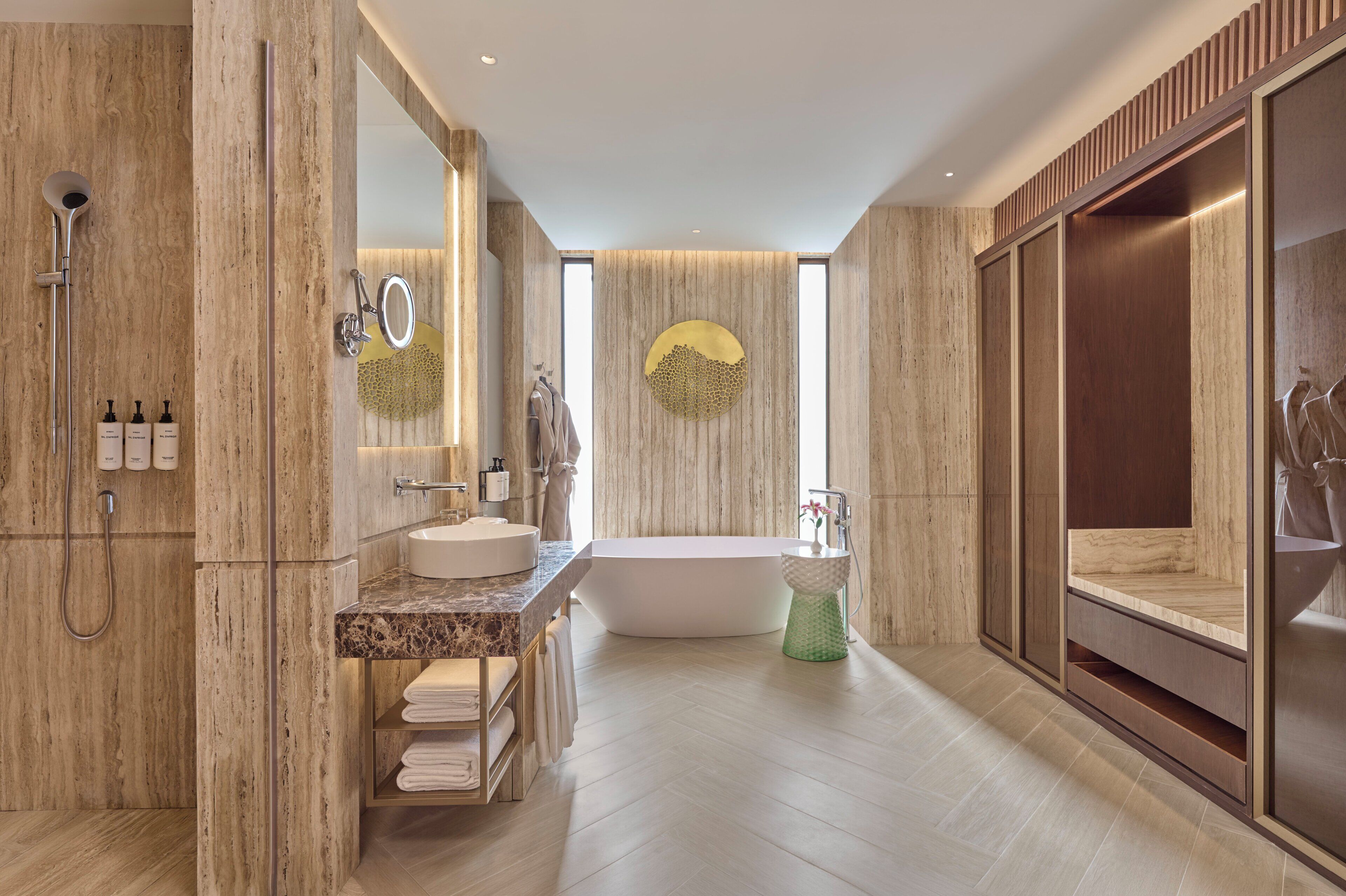 A modern bathroom with a freestanding bathtub, a vanity with a marble countertop, and a large mirror.