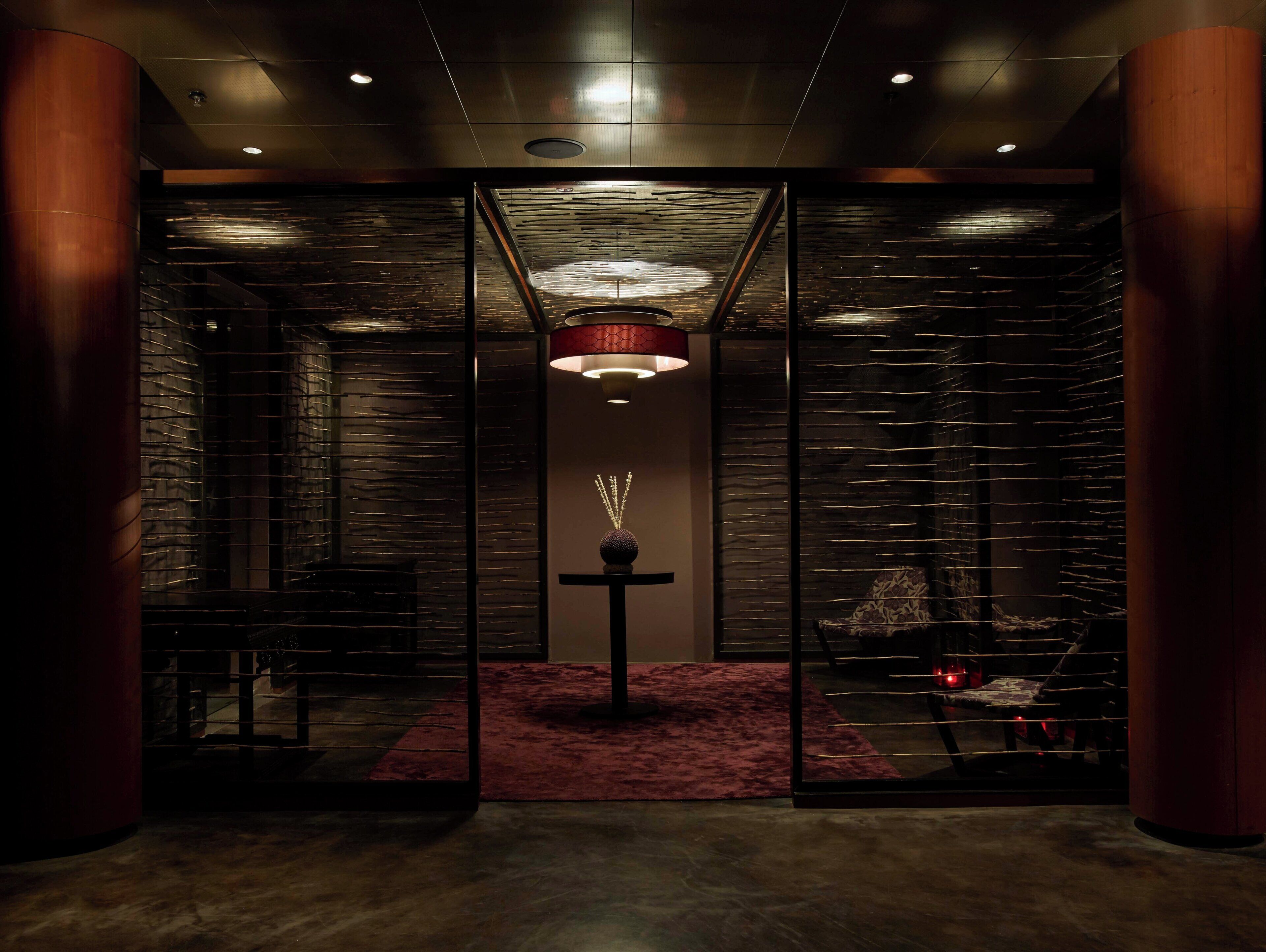 A modern interior with a central light fixture, a red carpet, and a patterned wall.