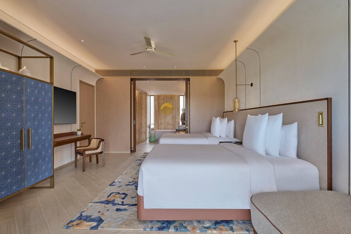 Ein modernes Hotelzimmer mit einem großen Bett, einem Schreibtisch, einem Kleiderschrank und einem Fernseher.