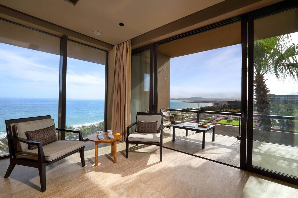 Een ruim balkon met uitzicht op zee, voorzien van een bank, stoelen en een kleine tafel.