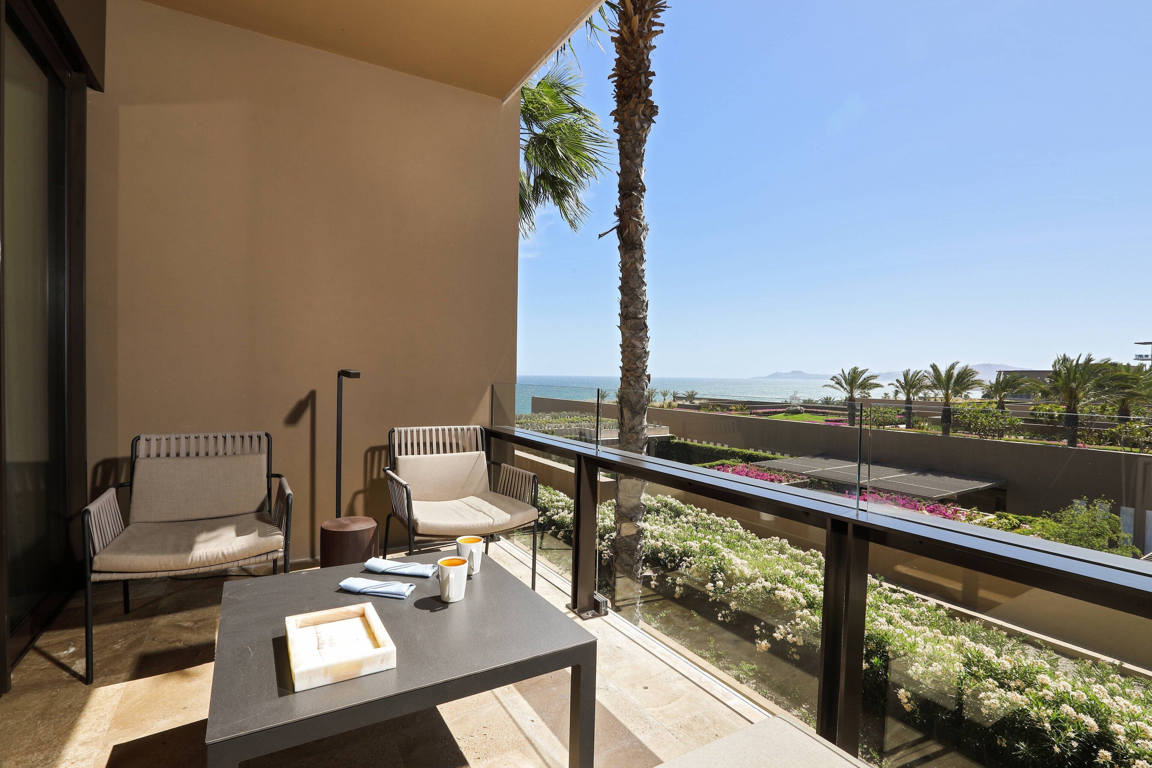 Een balkon met twee stoelen, een tafel en uitzicht op zee.