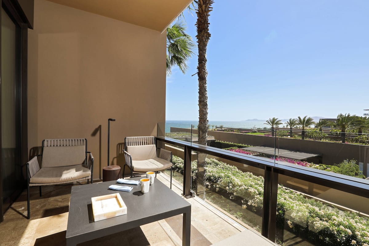 Een balkon met twee stoelen, een tafel en uitzicht op zee.