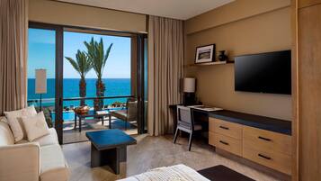 Habitación de hotel con balcón, cama, escritorio y televisión.