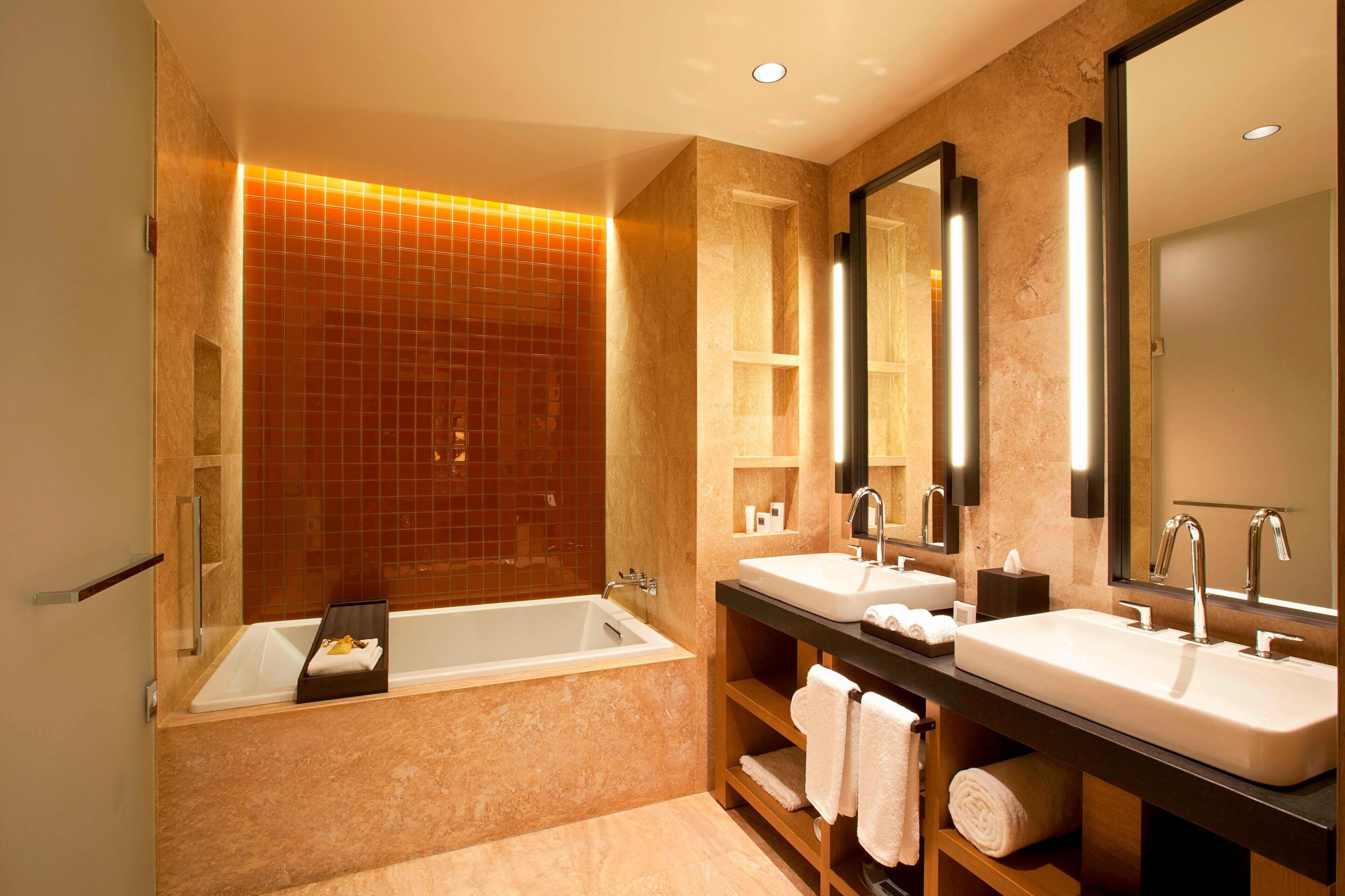 A modern bathroom with a large bathtub, two sinks, and a mirror.