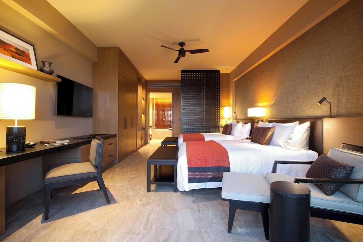 Een moderne hotelkamer met een groot bed, een bureau, een stoel, een bank en een plafondventilator.