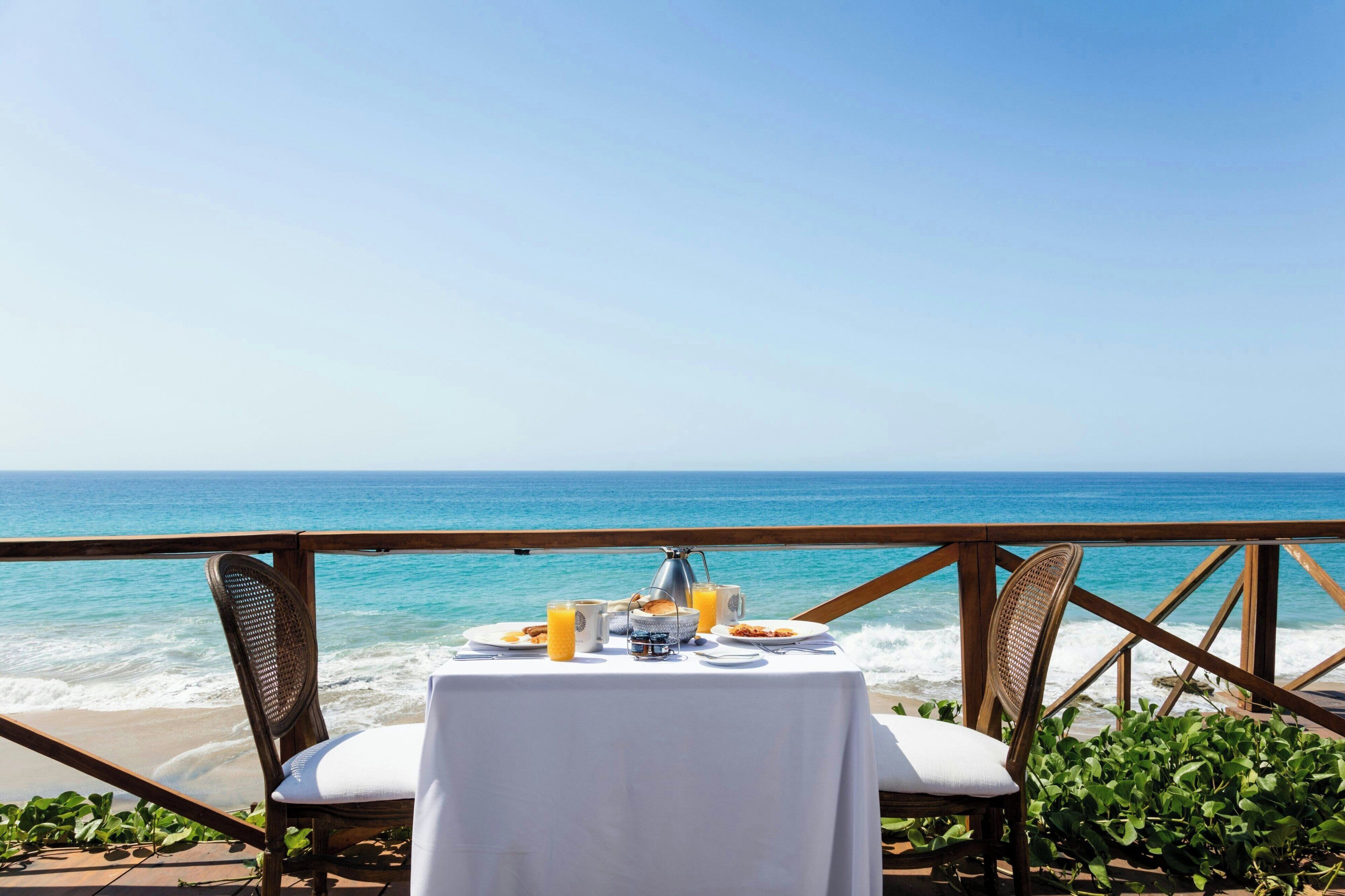 A table set for breakfast with a view of the ocean.