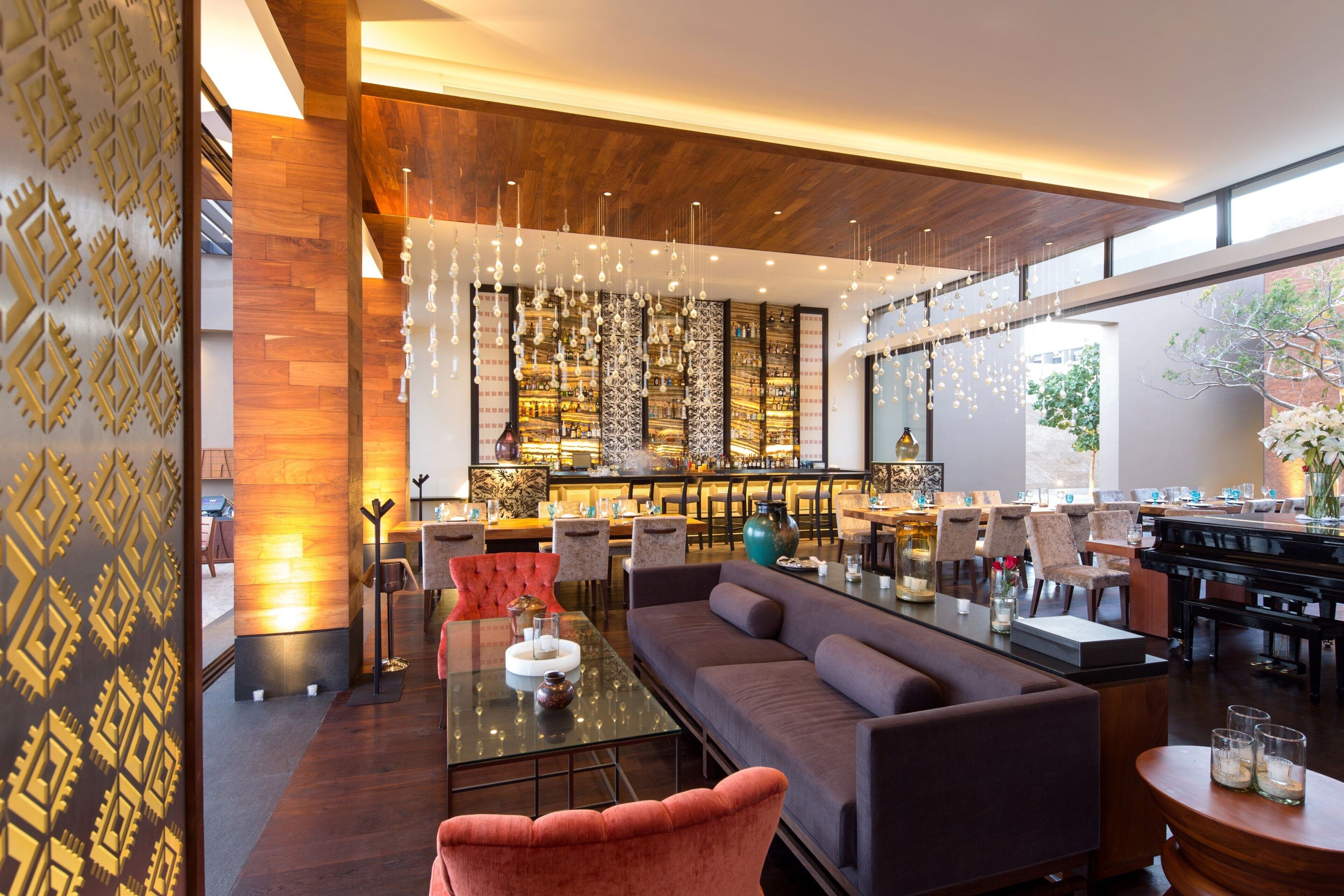 Um saguão de hotel moderno com área de bar, assentos e um piano.