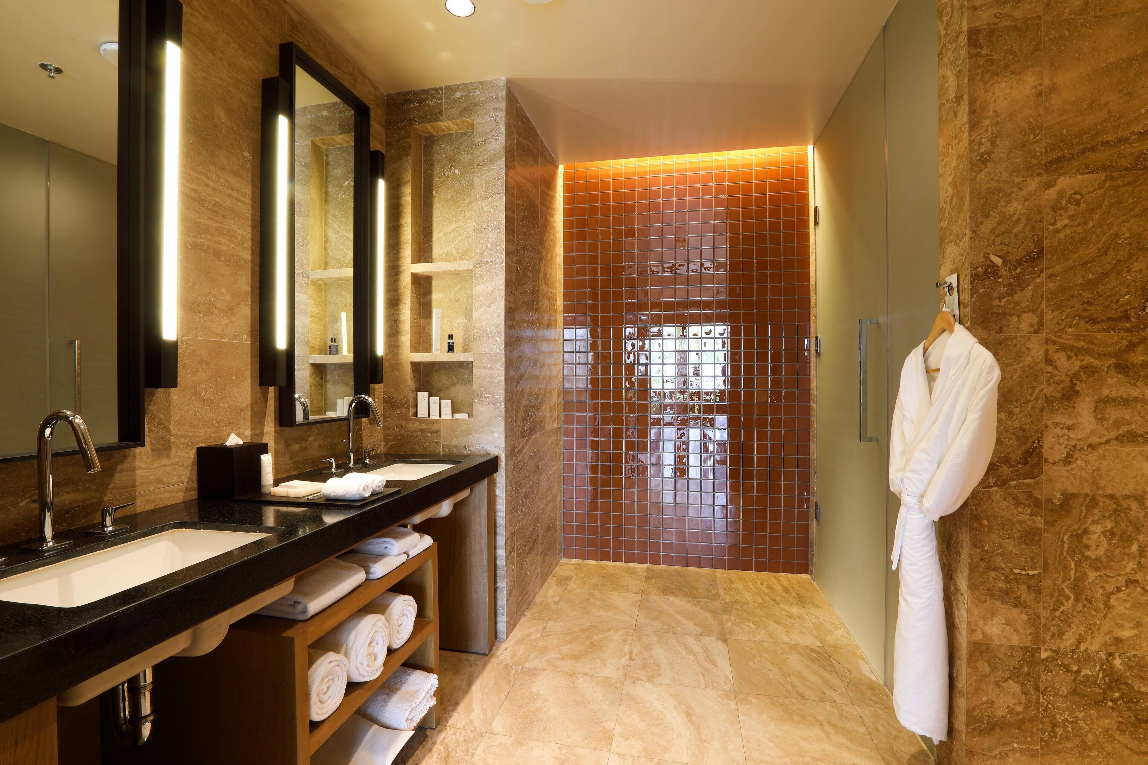 Une salle de bain moderne avec deux vasques, un grand miroir et un peignoir accroché au mur.