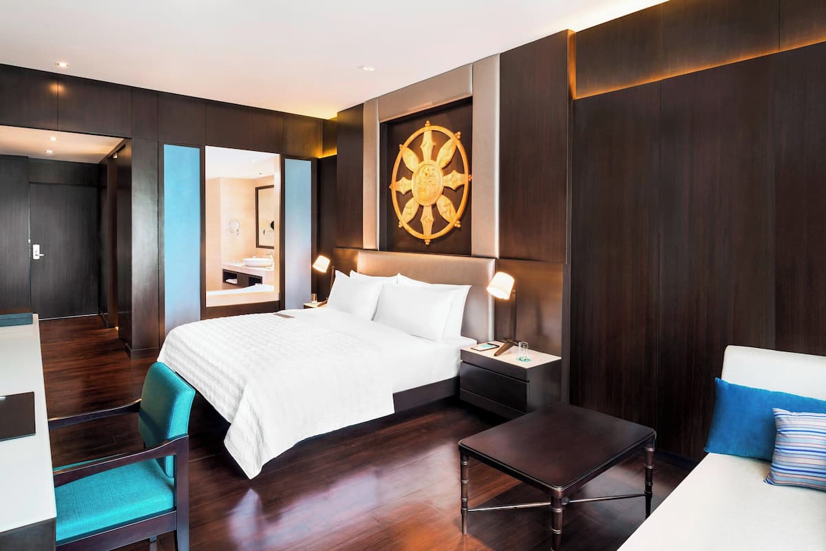 Una habitació d'hotel moderna amb un llit gran, taules de nit, un escriptori i una cadira.