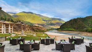 A terrace with wicker furniture and a river view. - Le Meridien Paro, Riverfront (Paro)