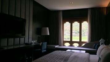 A hotel room with a bed, a desk, a chair, a television, and a window with curtains.