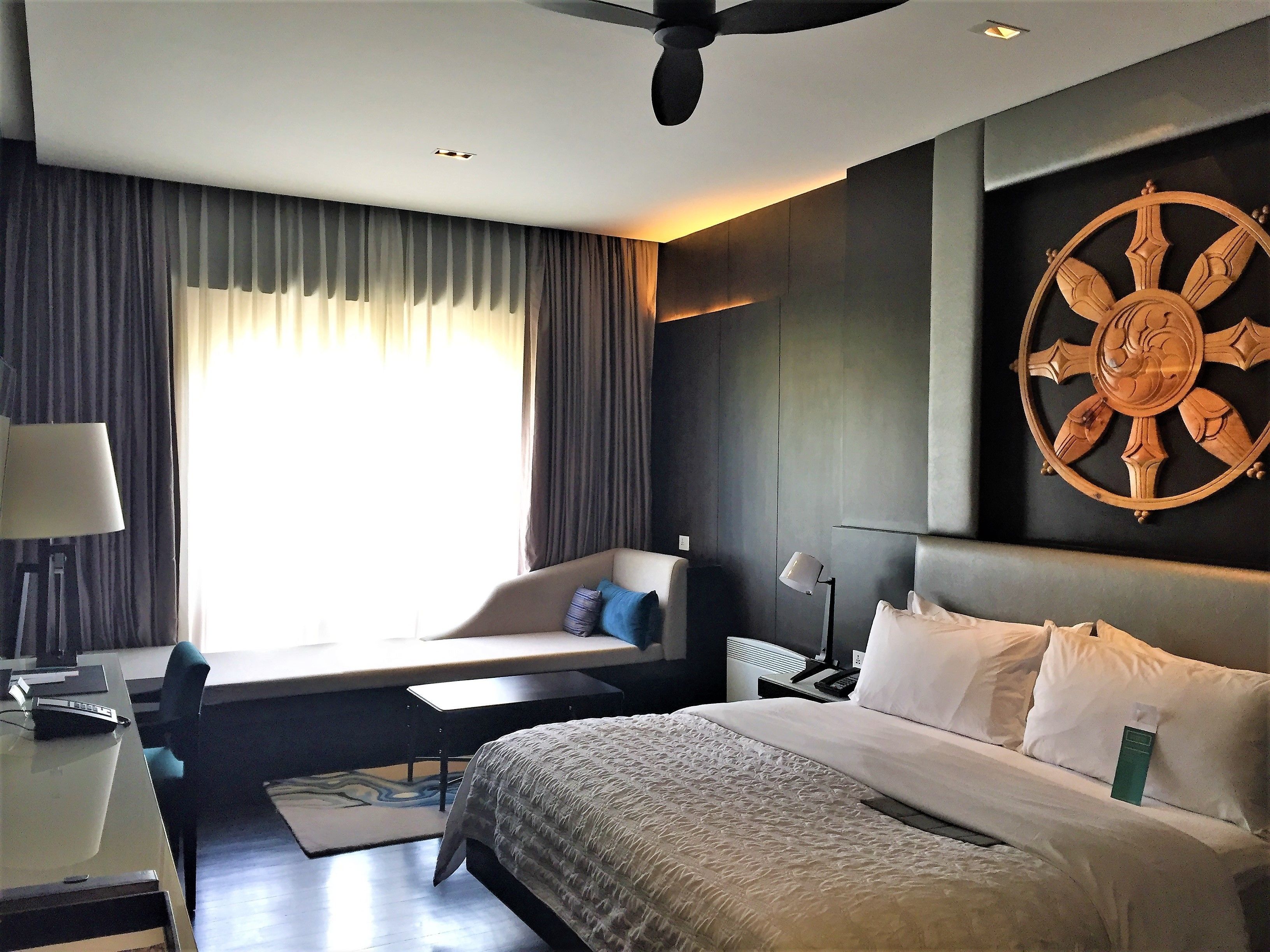 Habitación de hotel moderna con una cama grande, un escritorio, una silla y vistas al exterior.