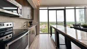 A modern kitchen with a large window, a built-in oven, and a dining area with a view.
