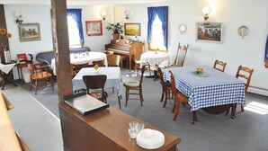A dining area with multiple tables and chairs, a piano, and wall-mounted artwork. - Die Heimat Country Inn (Homestead)