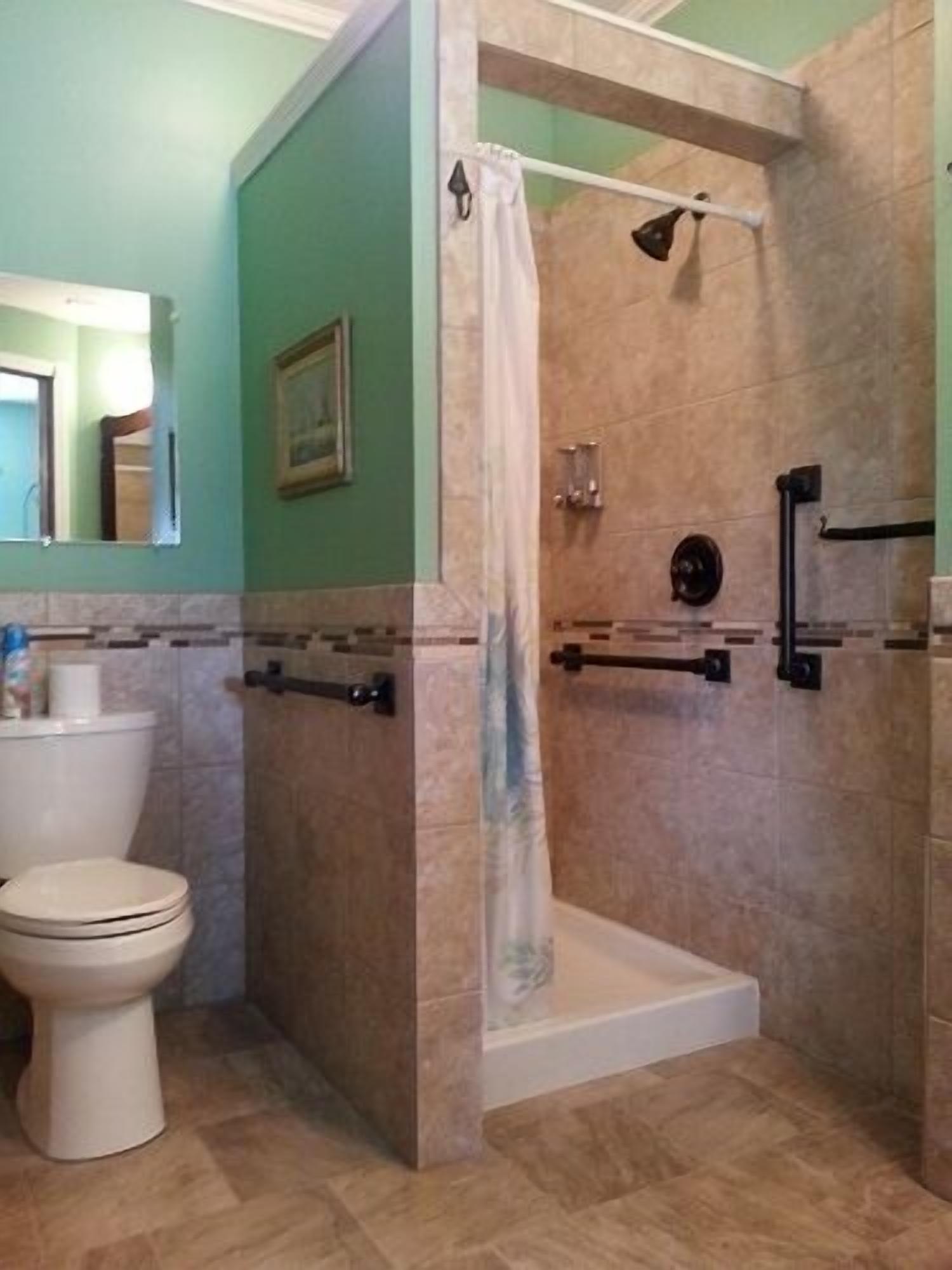 A bathroom with a toilet, a shower with a glass door, and a mirror.