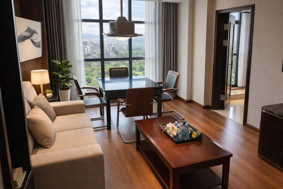 Ein modernes Hotelzimmer mit großem Fenster, einer Couch, einem Esstisch und einem Couchtisch.