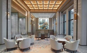 Ein modernes Interieur mit einer zentralen Bar, Sitzgelegenheiten und großen Fenstern.
