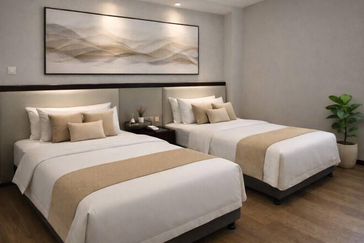 Ein Hotelzimmer mit zwei Betten, einem großen abstrakten Gemälde an der Wand, einem Nachttisch und einer Topfpflanze.