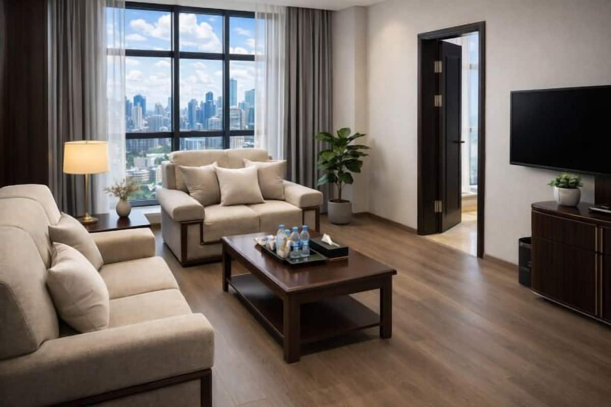 Ein modernes Hotelzimmer mit einer Couch, einem Couchtisch, einem Fernseher und Blick auf die Stadt.