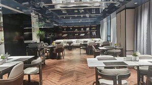 A modern restaurant with a herringbone floor, wooden tables, and chairs.