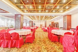 A banquet hall with round tables and red chairs, carpeted floor, and ornate ceiling. - Zouping Hotel (Binzhou)