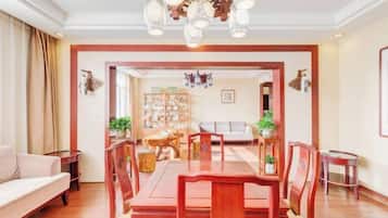 Un coin repas avec une table et des chaises en bois, un canapé et un lustre.