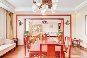 Un comedor con mesa y sillas de madera, un sofá y una araña.