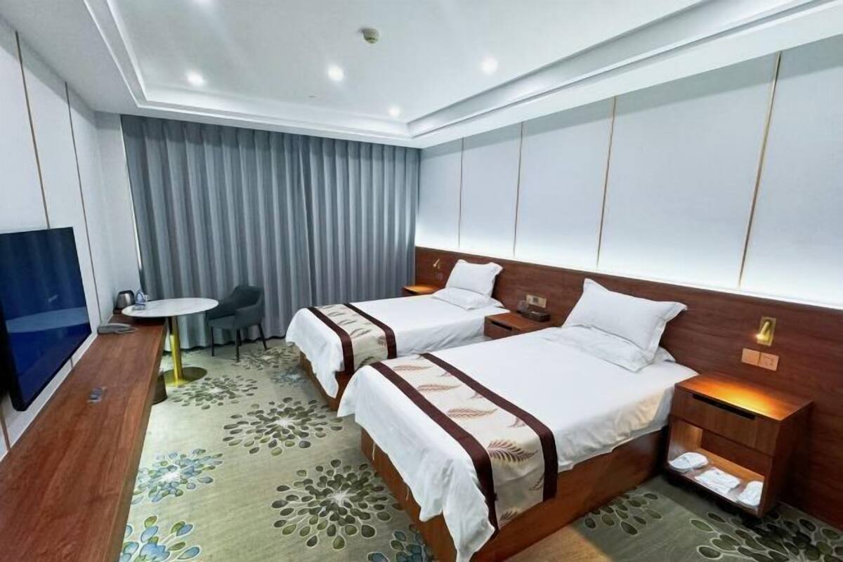 Habitación de hotel con dos camas, televisión, escritorio y una silla.