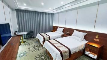 A hotel room with two beds, a TV, a desk, and a chair.