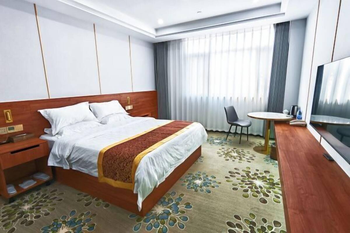 Una habitación de hotel con cama, mesita de noche, televisor y una pequeña mesa redonda.