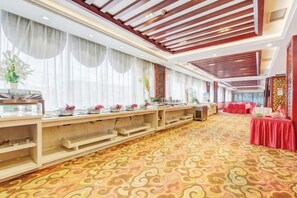 Un salón de banquetes con una larga mesa, manteles rojos y una alfombra estampada.