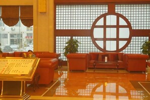 Un vestíbulo con mostrador de recepción, zona de estar y un ventanal grande con diseño de cuadrícula.