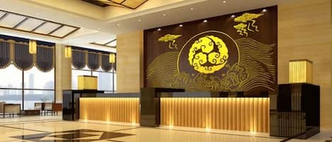 A hotel lobby with a reception desk, large windows, and a decorative wall mural.