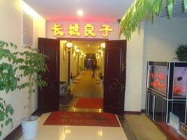 Entrada de hotel con alfombra roja, un mostrador de recepción y un letrero con caracteres chinos.