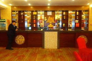 A hotel reception area with a counter, a red chair, and a decorative lamp. - Zouping Hotel (Binzhou)