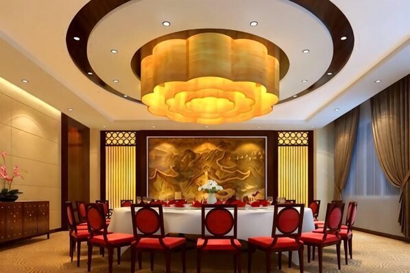 A dining area with a round table, red chairs, and a large chandelier.