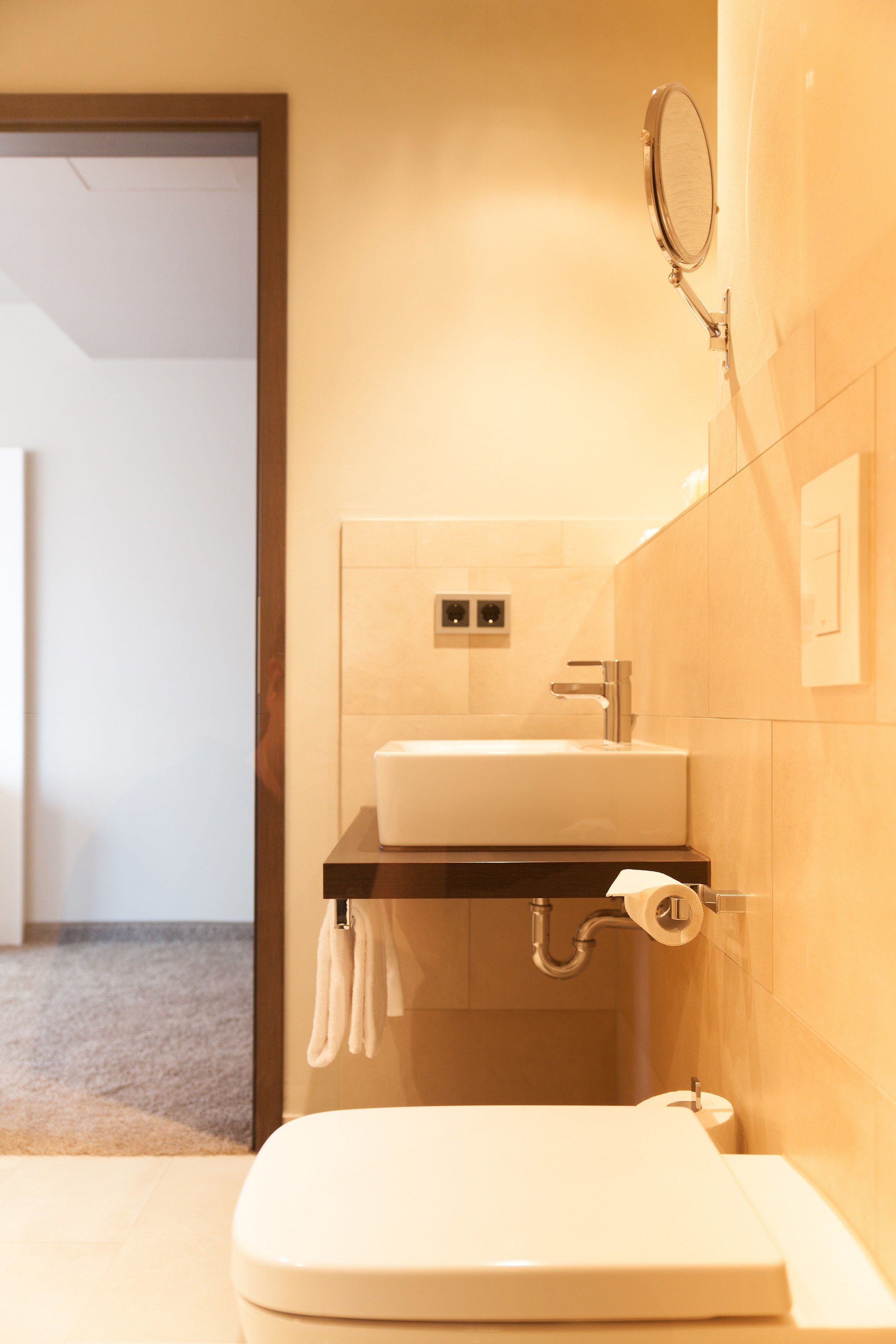 A modern bathroom with a toilet, sink, and mirror.