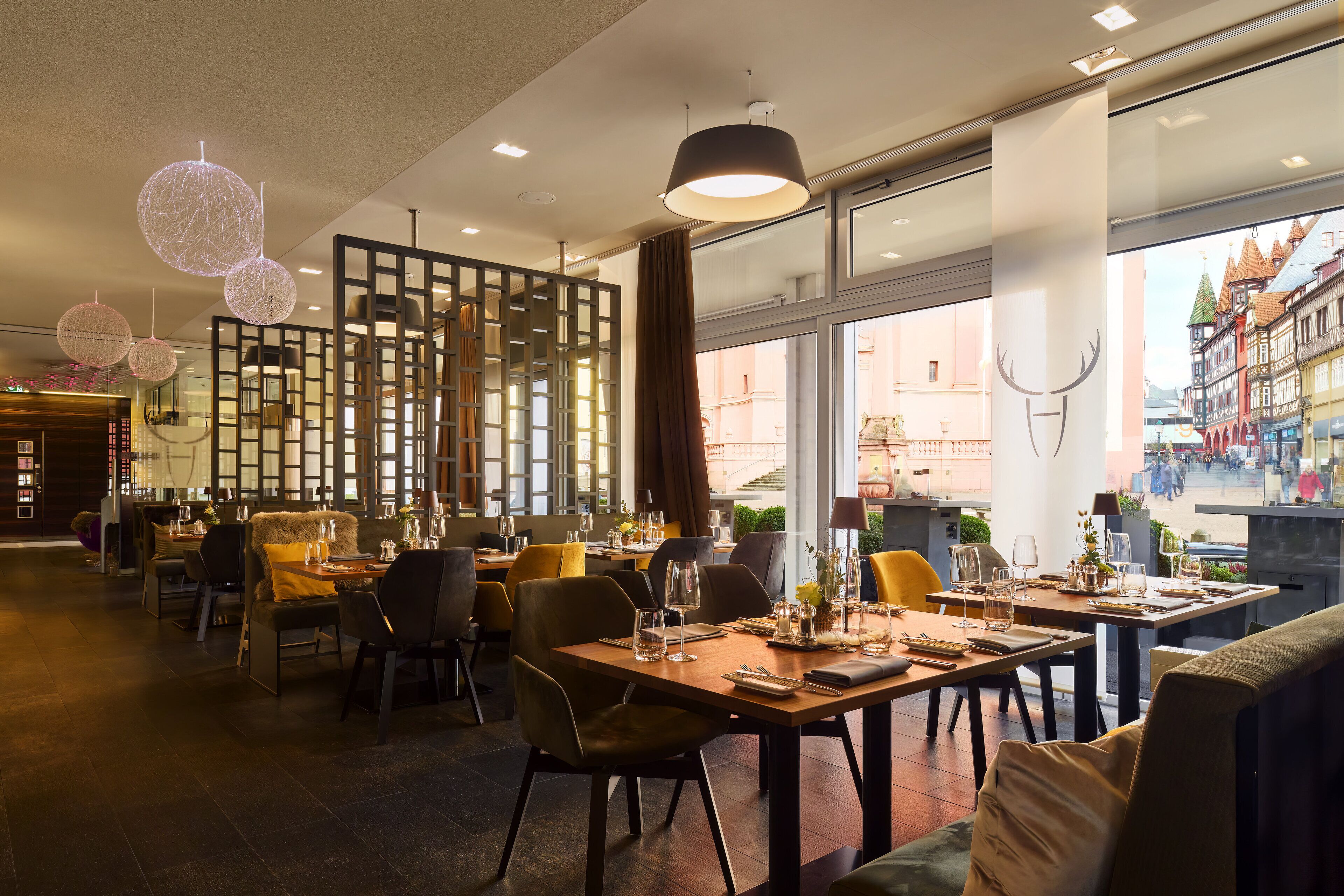 Ein Restaurant mit mehreren Speisetafeln, Stühlen und hängenden, kugelförmigen Lampen.