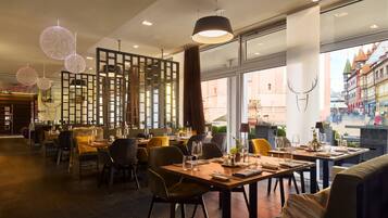 Ein Restaurant mit mehreren Speisetafeln, Stühlen und hängenden, kugelförmigen Lampen.