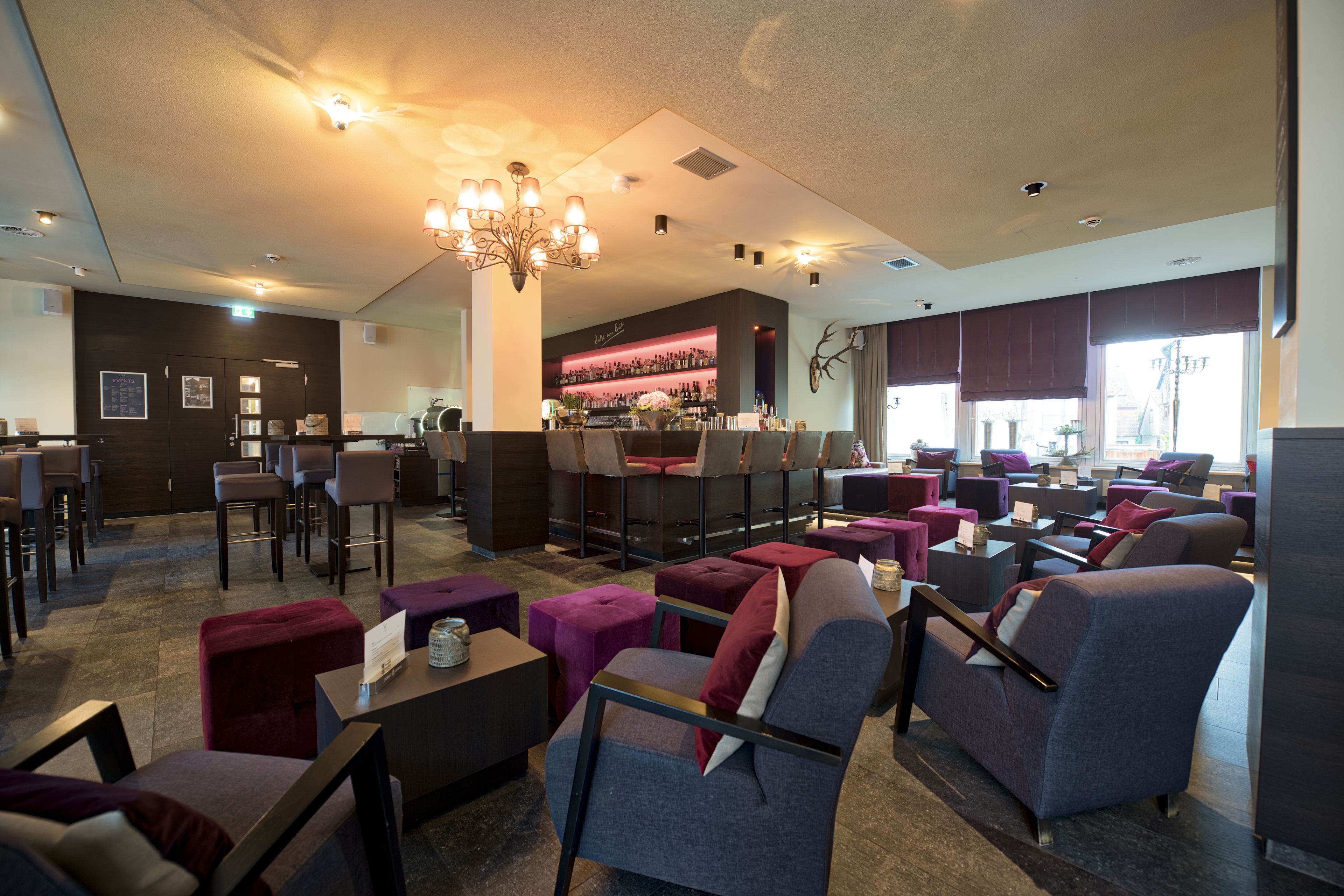 A modern lounge area with multiple seating options, a bar, and a decorative wall.