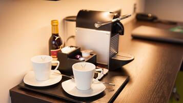 A coffee machine with a cup of coffee and a bottle of wine on a tray.