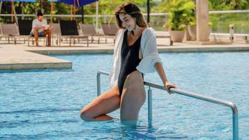 A person sitting on a poolside ledge.