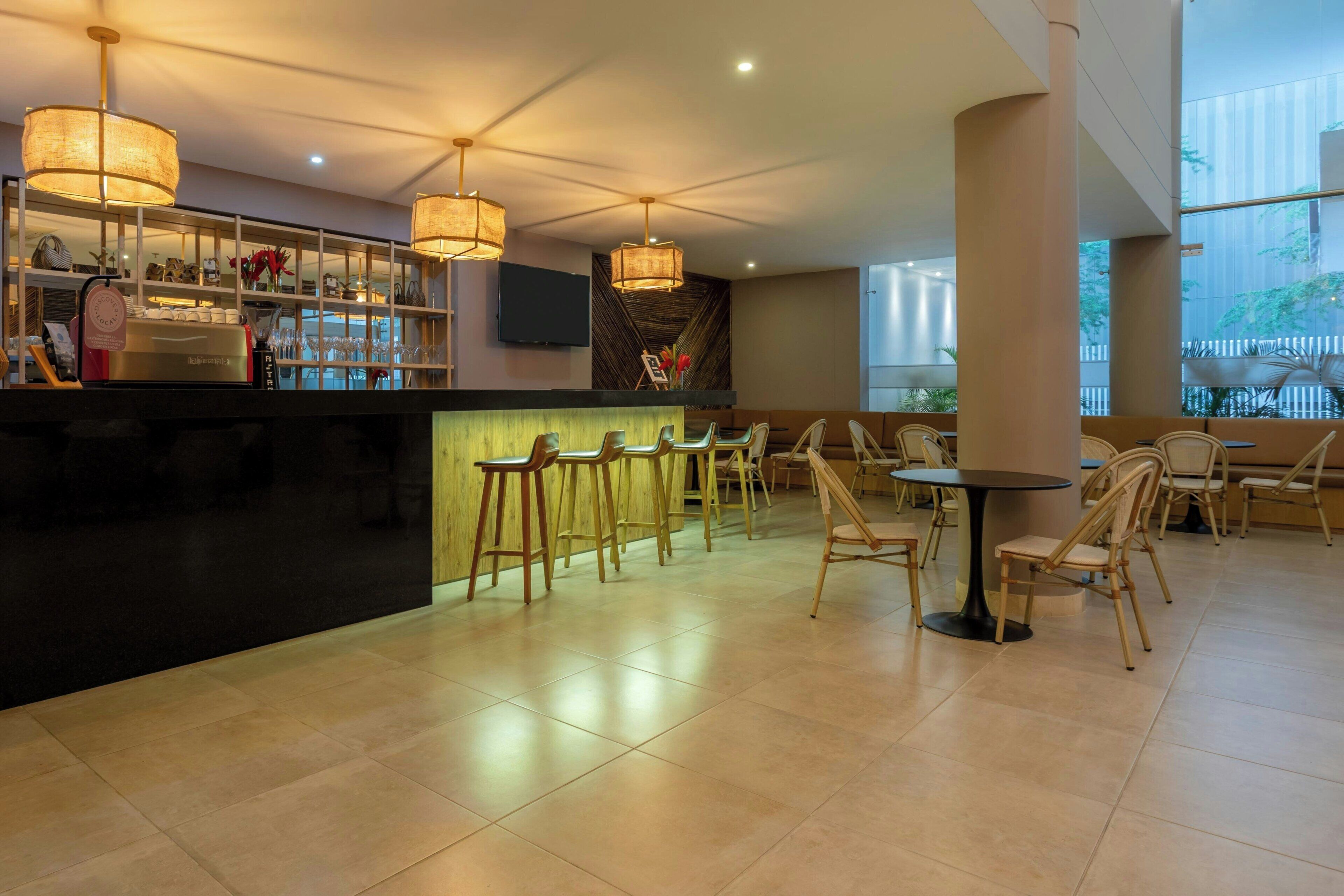 A modern bar area with a counter, bar stools, and a seating area with tables and chairs.