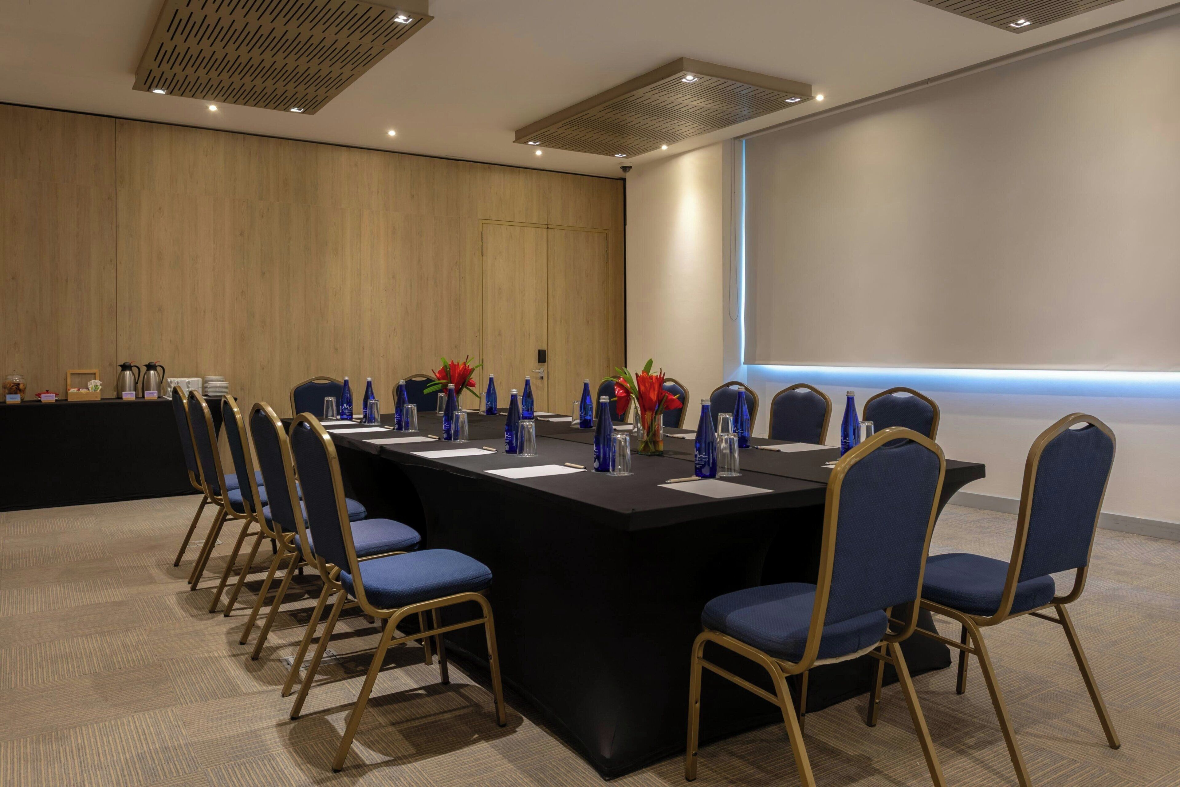 A conference room with a long table, blue chairs, and a podium.