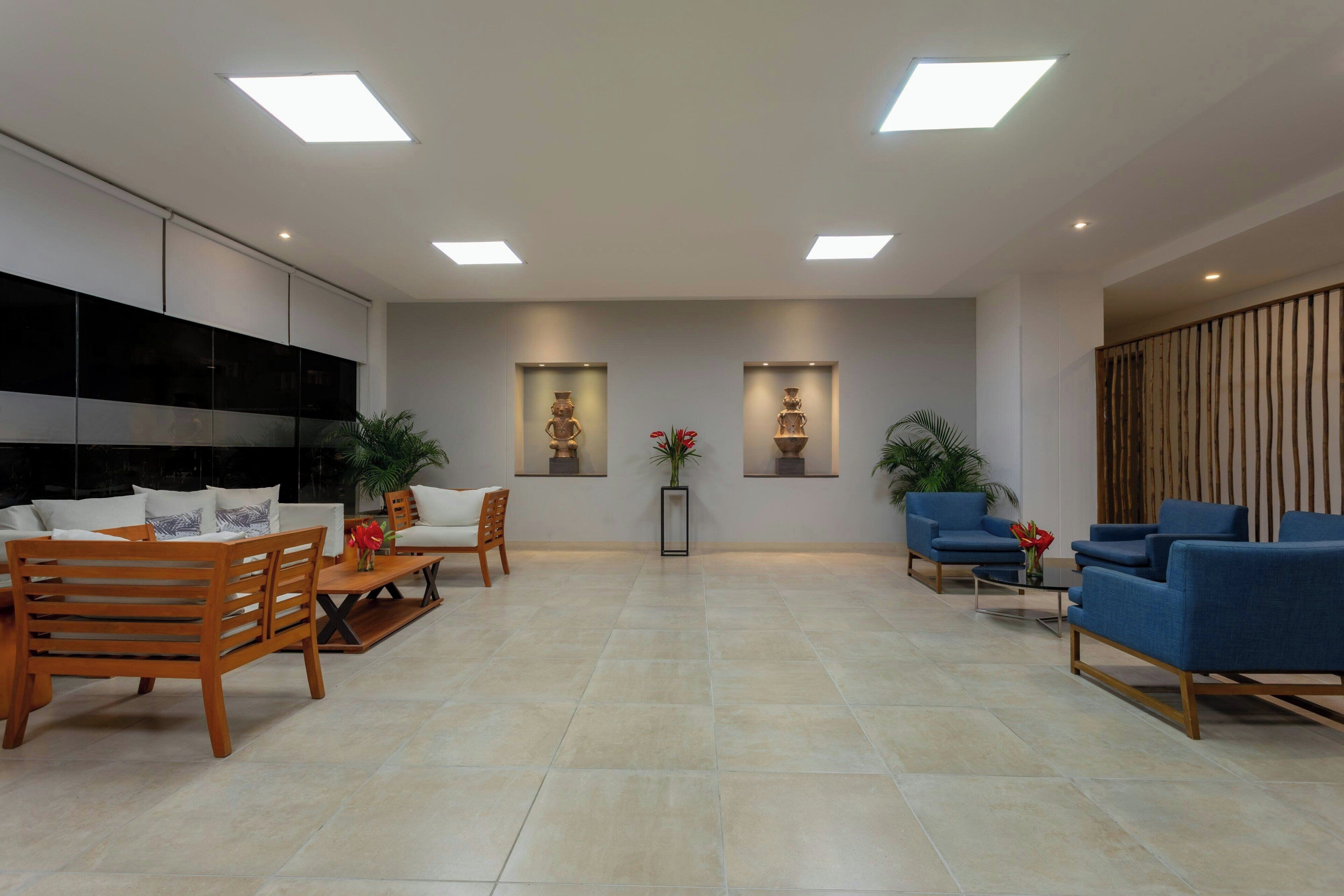 A modern waiting area with a sofa, chairs, and a coffee table. There are two wall-mounted shelves with decorative items.