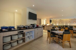 Uma sala de jantar moderna com buffet, cadeiras de madeira e uma TV de tela plana fixada na parede.